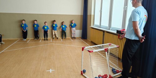 Dzieci na sali gimnastycznej rzucają piłkami do bramki