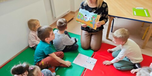 Nauczycielka czyta dzieciom książkę do czytania uczestniczącego pt. „Zwierzęta w lesie